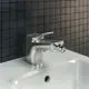 Bidetarmatur von Ideal Standard in Silber, mit einem Auslauf von 133 mm und einem Hebel zur Temperatur- und Wassermengenregelung. Auf einem weißen Waschbecken platziert.